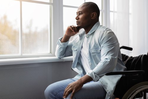 Bilde mann i rullestol som ser tankefullt ut av vinduet