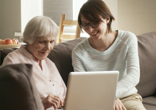 Bilde av to personer som sitter å ser på en PC